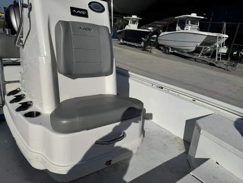 Slide: The Image of Avid FS 2021 boat interior with gray seating and cup holders, docked near other boats. - 6