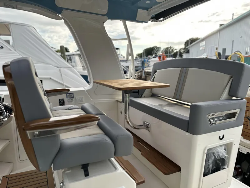 Slide: The Image of 2025 Boston Whaler 380 Realm interior with seating and table, docked at marina. - 13