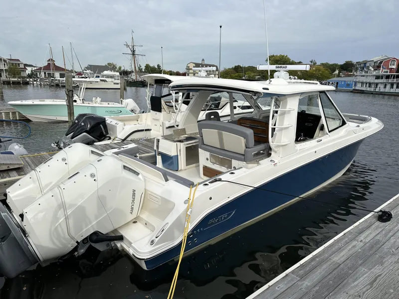 Slide: The Image of 2025 Boston Whaler 380 Realm boat docked in a marina, featuring sleek design and powerful engines. - 2