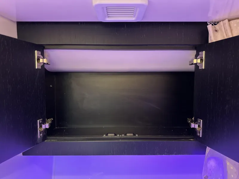 Slide: The Image of Open cabinet with purple lighting inside a 2025 Boston Whaler 380 Realm boat. - 30