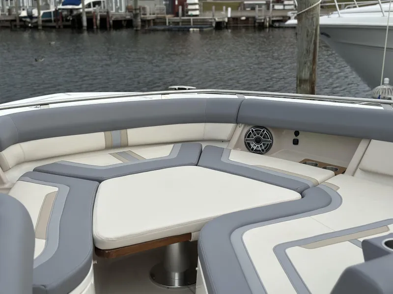 Slide: The Image of 2025 Boston Whaler 380 Realm boat interior with cushioned seating and water view. - 37