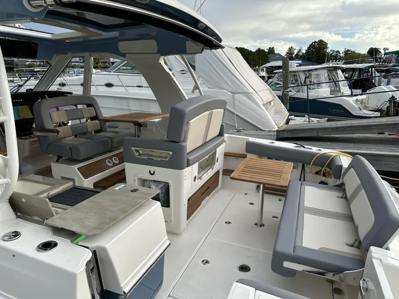 Slide: The Image of 2025 Boston Whaler 380 Realm boat interior with seating and table at marina. - 8