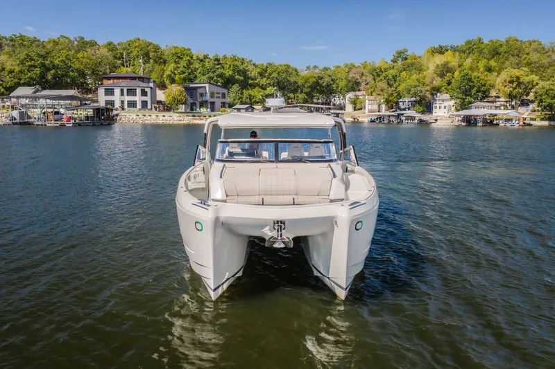 The Image of 2025 Catamaran YOT 36 on a serene lake, surrounded by lush greenery and waterfront homes. - 3