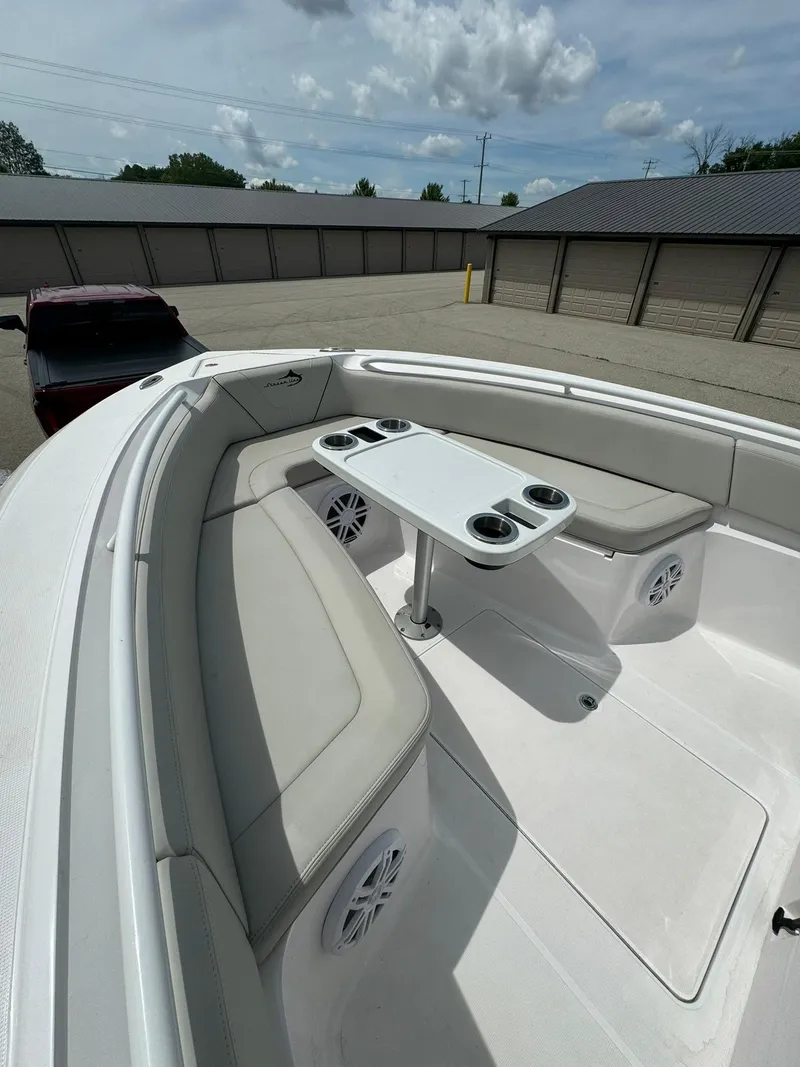 Slide: The Image of 2022 Streamline Center Console boat with cushioned seating and table, parked outdoors. - 15