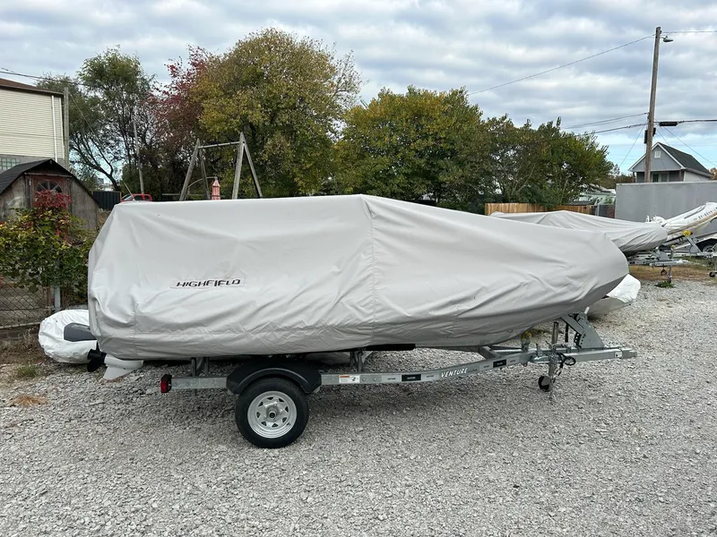 Slide: The Image of 2024 Highfield Sport 390 boat covered on trailer, parked outdoors. - 2