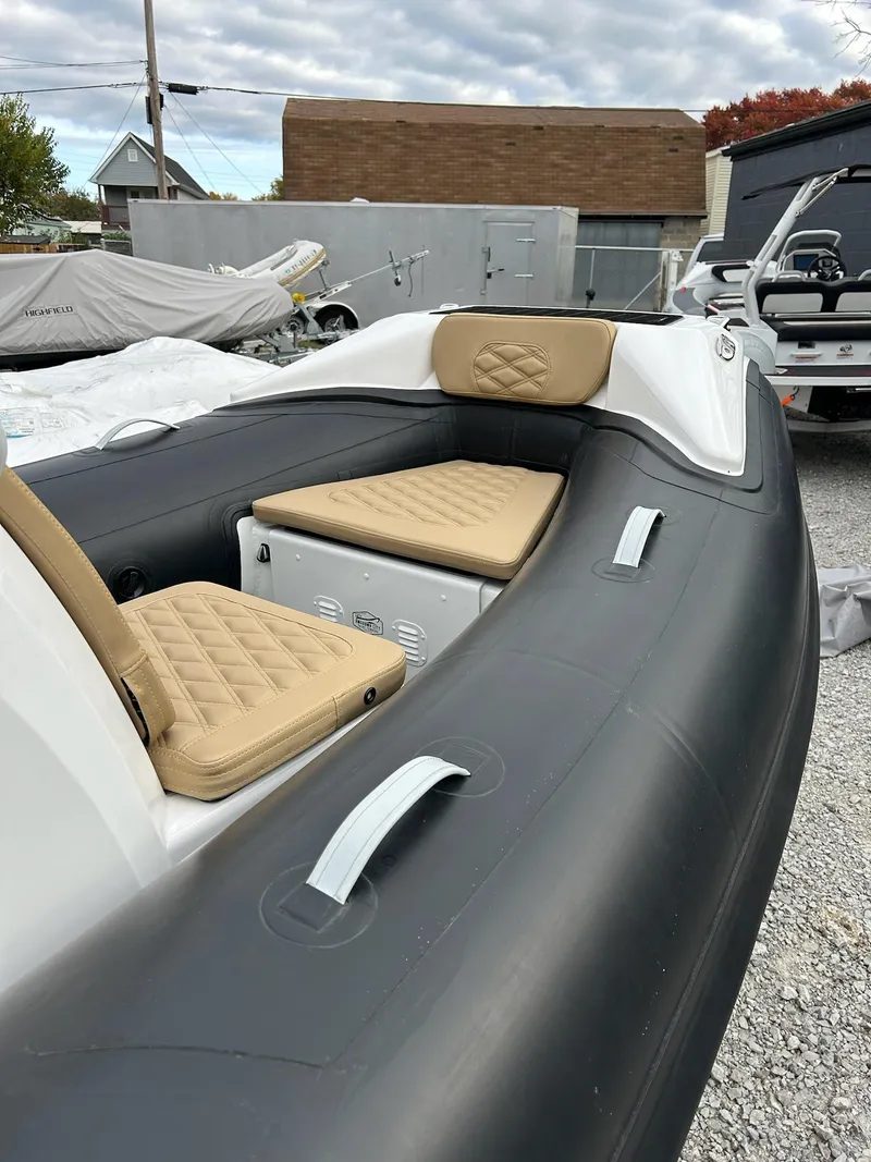 Slide: The Image of 2024 Highfield Sport 390 inflatable boat with beige seating, docked outdoors. - 4