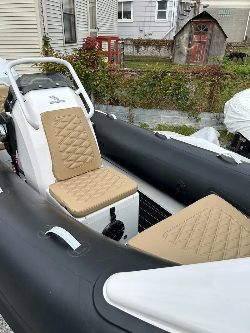 Slide: The Image of 2024 Highfield Sport 390 boat with tan quilted seats, parked outdoors. - 5