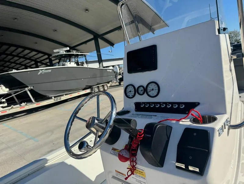 Slide: The Image of 2021 Avid 21 FS boat console with steering wheel and gauges in a marina. - 13