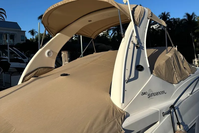 Slide: The Image of 2002 Sea Ray 320 Sundancer boat with beige canopy, docked in a marina. - 2