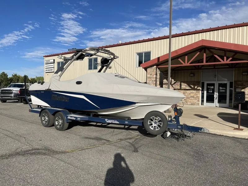 Slide: The Image of 2017 Malibu 21 VLX boat on trailer outside a building under a clear sky. - 12