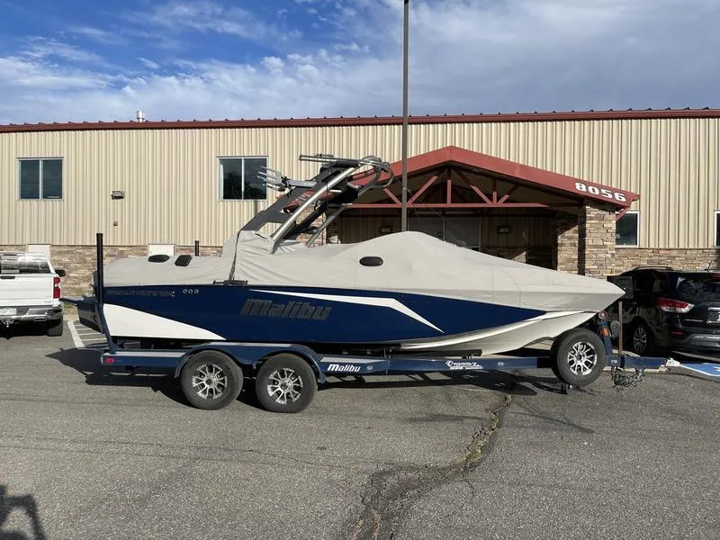 Slide: The Image of 2017 Malibu 21 VLX boat on trailer, covered, parked outside a building. - 13
