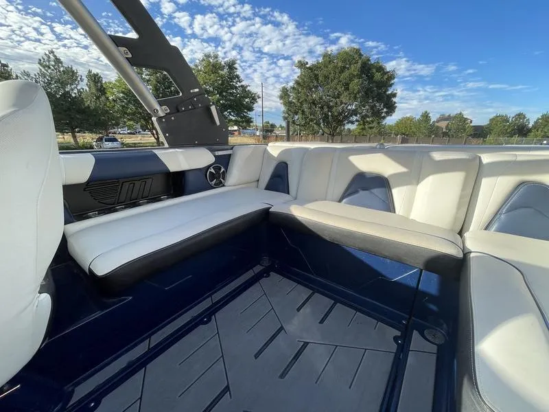 Slide: The Image of 2017 Malibu 21 VLX boat interior with white seating and blue flooring under a clear sky. - 18