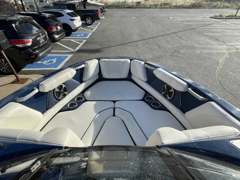 Slide: The Image of 2017 Malibu 21 VLX boat with spacious white seating in a parking lot. - 21