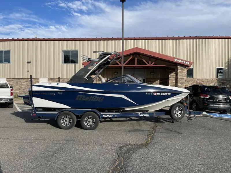 Slide: The Image of 2017 Malibu 21 VLX boat on trailer, parked outside a building. - 5