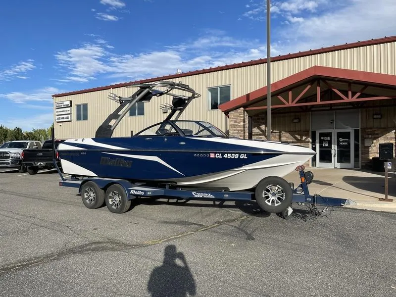 Slide: The Image of 2017 Malibu 21 VLX boat on trailer outside a building under a clear sky. - 6