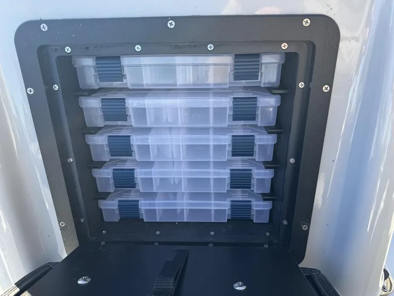 Slide: The Image of 2024 Avid 21 FS Platinum tackle storage compartment with organized plastic boxes. - 10