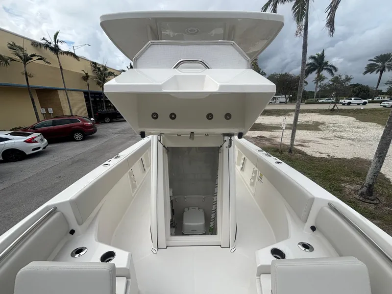Slide: The Image of 2025 Sailfish 232 CC boat interior with open storage compartment, surrounded by palm trees. - 18