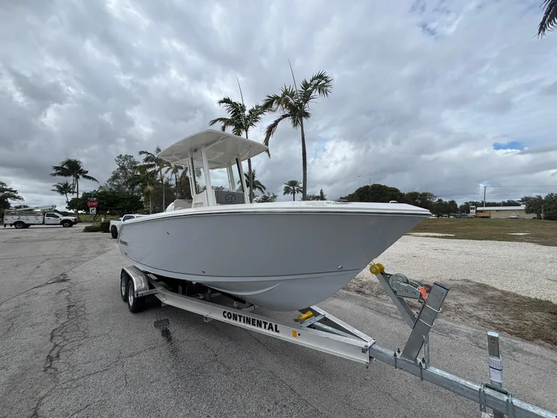 Slide: The Image of 2025 Sailfish 232 CC boat on trailer, parked near palm trees under cloudy sky. - 4