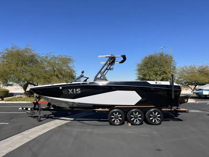 Slide: The Image of 2025 Axis A245 boat on trailer, parked outdoors under clear blue sky. - 1