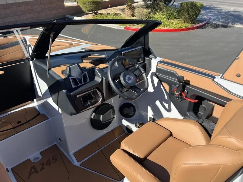 Slide: The Image of 2025 Axis A245 boat interior with modern dashboard and tan seating. - 10