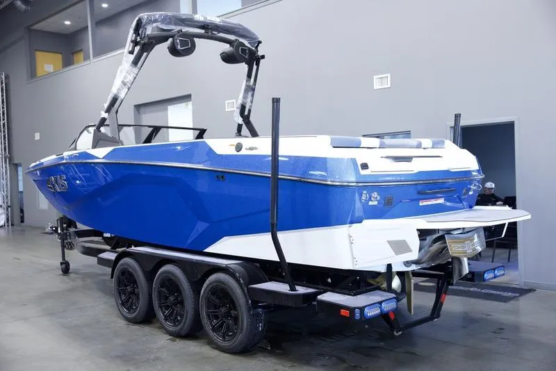 Slide: The Image of 2025 Axis A245 boat in blue on a triple-axle trailer, displayed indoors. - 4
