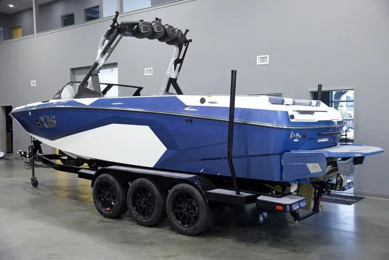 Slide: The Image of 2025 Axis A245 boat on trailer in showroom, blue and white design. - 4