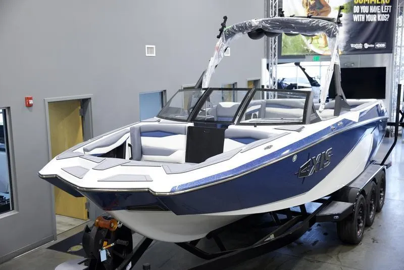 Slide: The Image of 2025 Axis A245 boat in showroom, blue and white design, on trailer. - 8