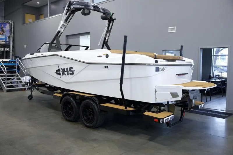 Slide: The Image of 2025 Axis T235 boat in showroom, white exterior, dual-axle trailer, modern design. - 4