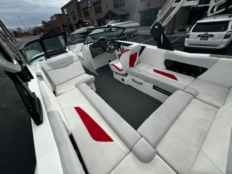 Slide: The Image of 2021 MasterCraft NXT22 boat interior with white and red seating, parked outdoors. - 12