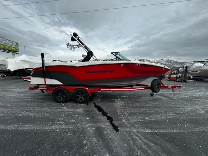 Slide: The Image of 2021 MasterCraft NXT22 boat on trailer, red and black design, parked outdoors. - 4