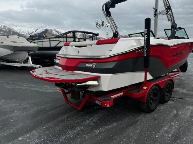 Slide: The Image of 2021 MasterCraft NXT22 boat in red and white on a trailer, parked outdoors. - 6