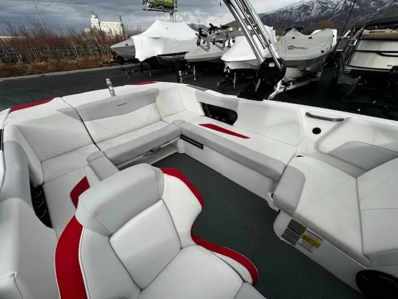 Slide: The Image of 2021 MasterCraft NXT22 boat interior with white and red seating, parked outdoors. - 9