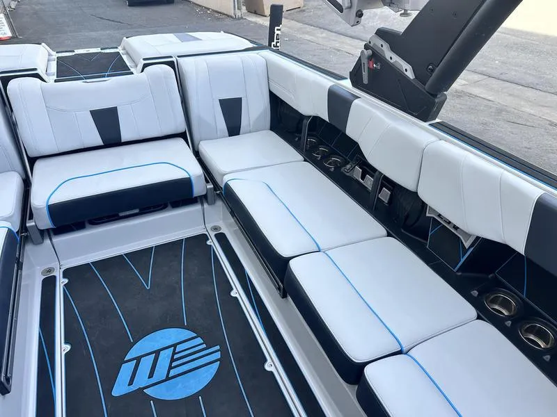 Slide: The Image of 2023 Malibu 23 LSV boat interior with white and black seating, blue accents, and logo on floor. - 12