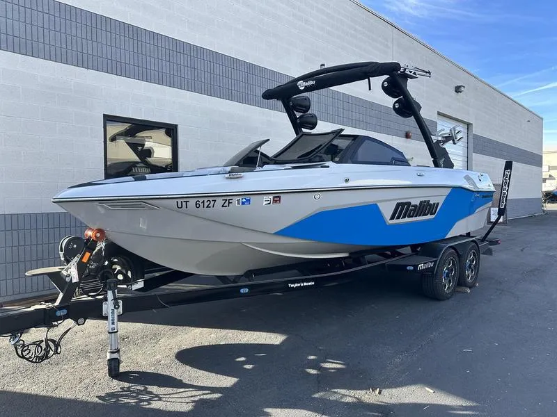 Slide: The Image of 2023 Malibu 23 LSV boat on trailer, parked outside a building. - 3