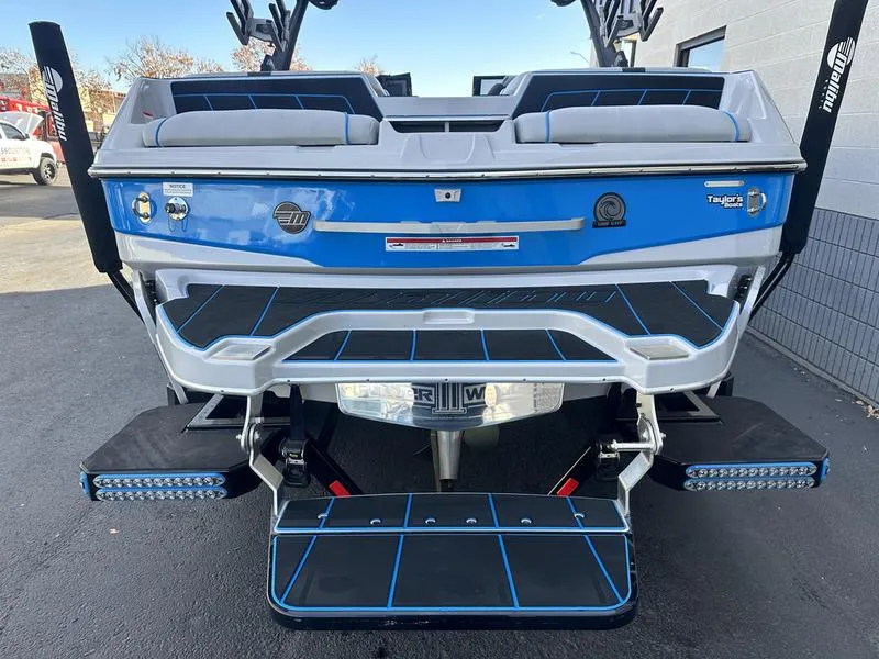 Slide: The Image of 2023 Malibu 23 LSV boat rear view with blue and white detailing. - 7