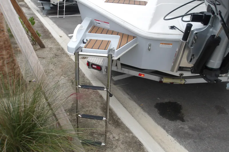 Slide: The Image of 2025 Ranger 2600 Bay boat with ladder and trailer, parked on pavement. - 8