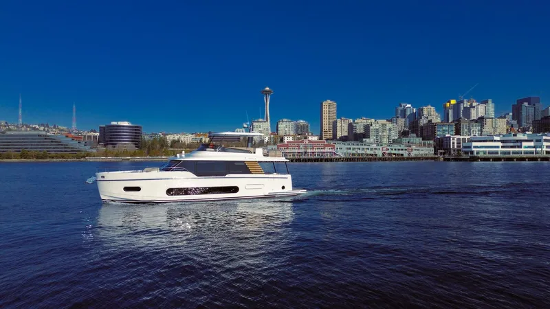 Slide: The Image of 2025 Azimut Magellano 60 yacht cruising near a city skyline under a clear blue sky. - 7