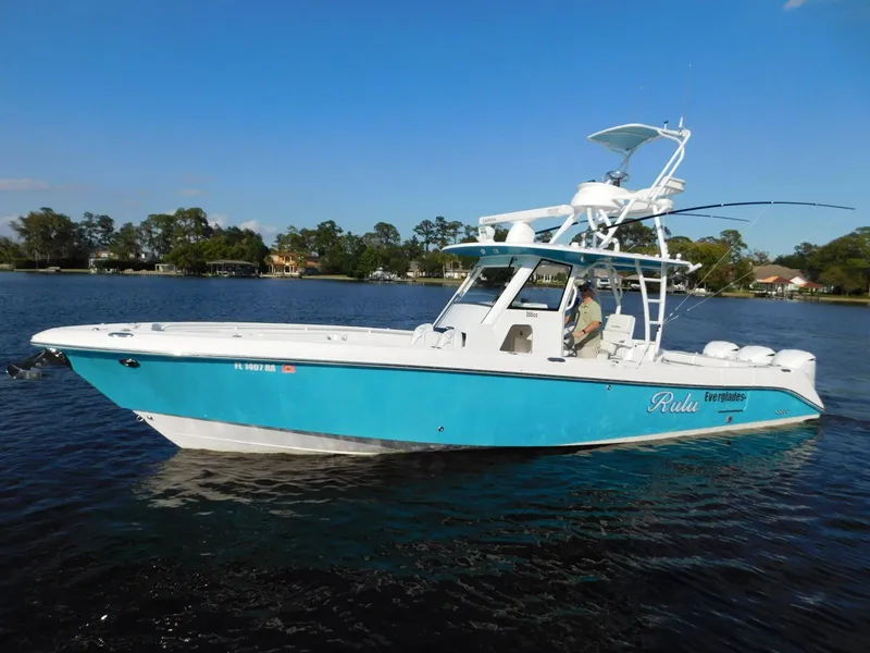 The Image of 2016 Everglades 355 Center Console boat on calm water, blue and white design. - 0