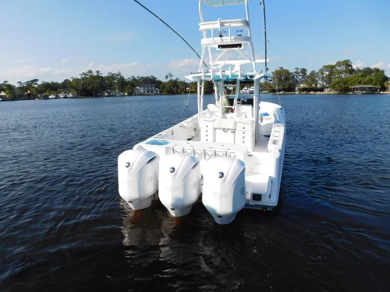 Slide: The Image of 2016 Everglades 355 Center Console boat with triple outboard engines on a calm lake. - 9