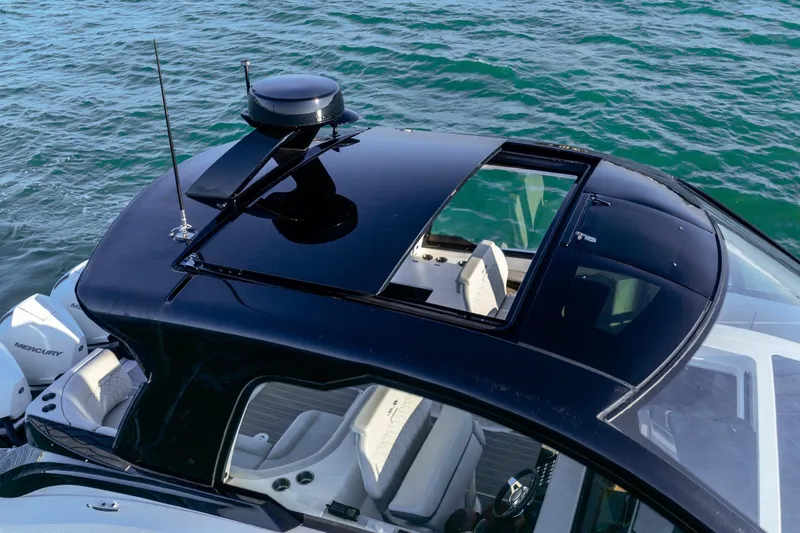 Slide: The Image of 2023 Sea Ray Sundancer 370 OB with sleek black roof, cruising on blue water. - 14