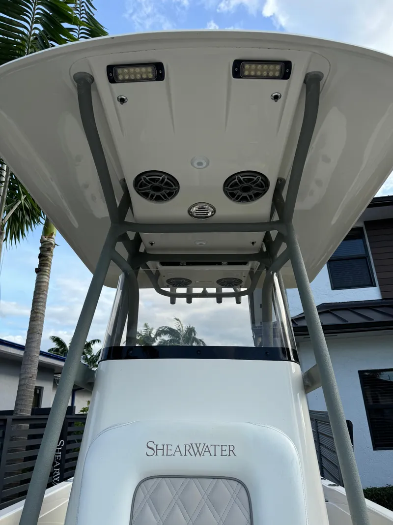 Slide: The Image of 2014 ShearWater 25LTZ boat with T-top and speakers, docked near a house. - 16