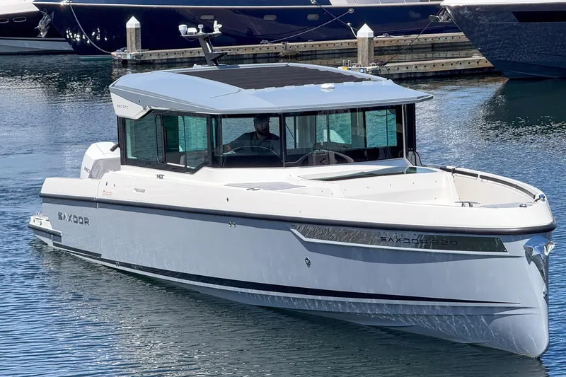 Slide: The Image of 2025 Saxdor 320 GTC boat on water, sleek design, modern cabin, docked in marina. - 2