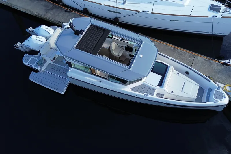 Slide: The Image of 2025 Saxdor 320 GTC boat docked, aerial view, sleek design, dual engines. - 4