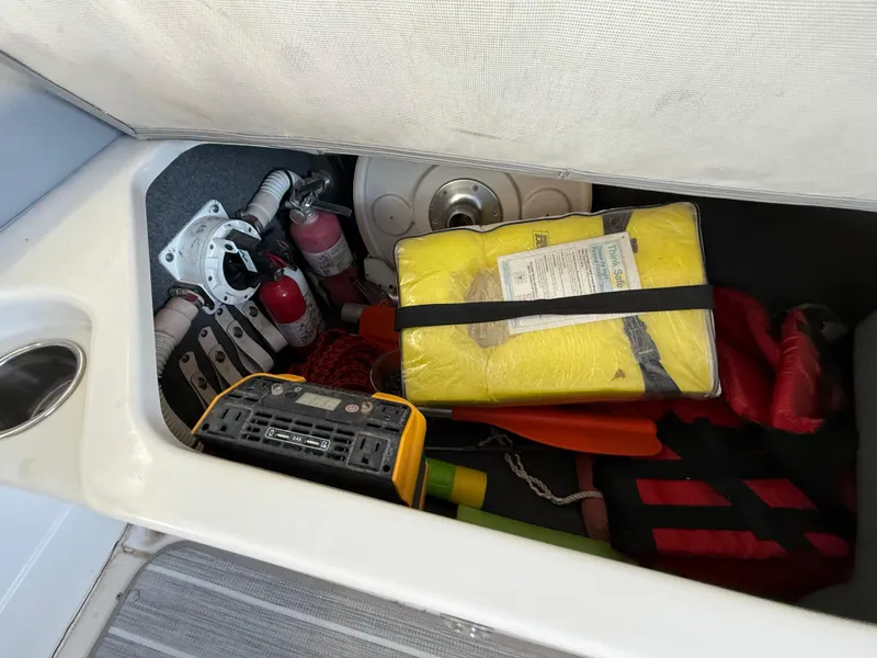 Slide: The Image of Storage compartment in a 2003 Sea Ray 270 Sundeck with safety equipment and tools. - 25