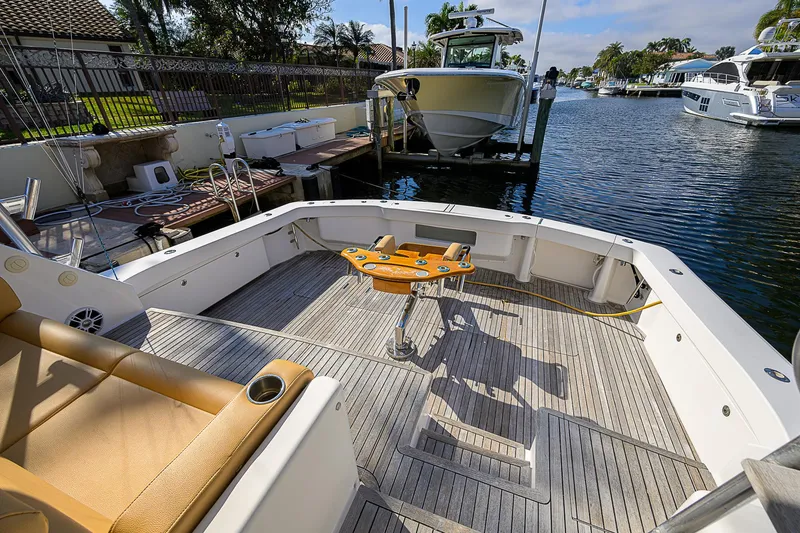 Slide: The Image of 2007 Viking 68 Convertible yacht deck with fishing chair, docked by a serene waterfront. - 24
