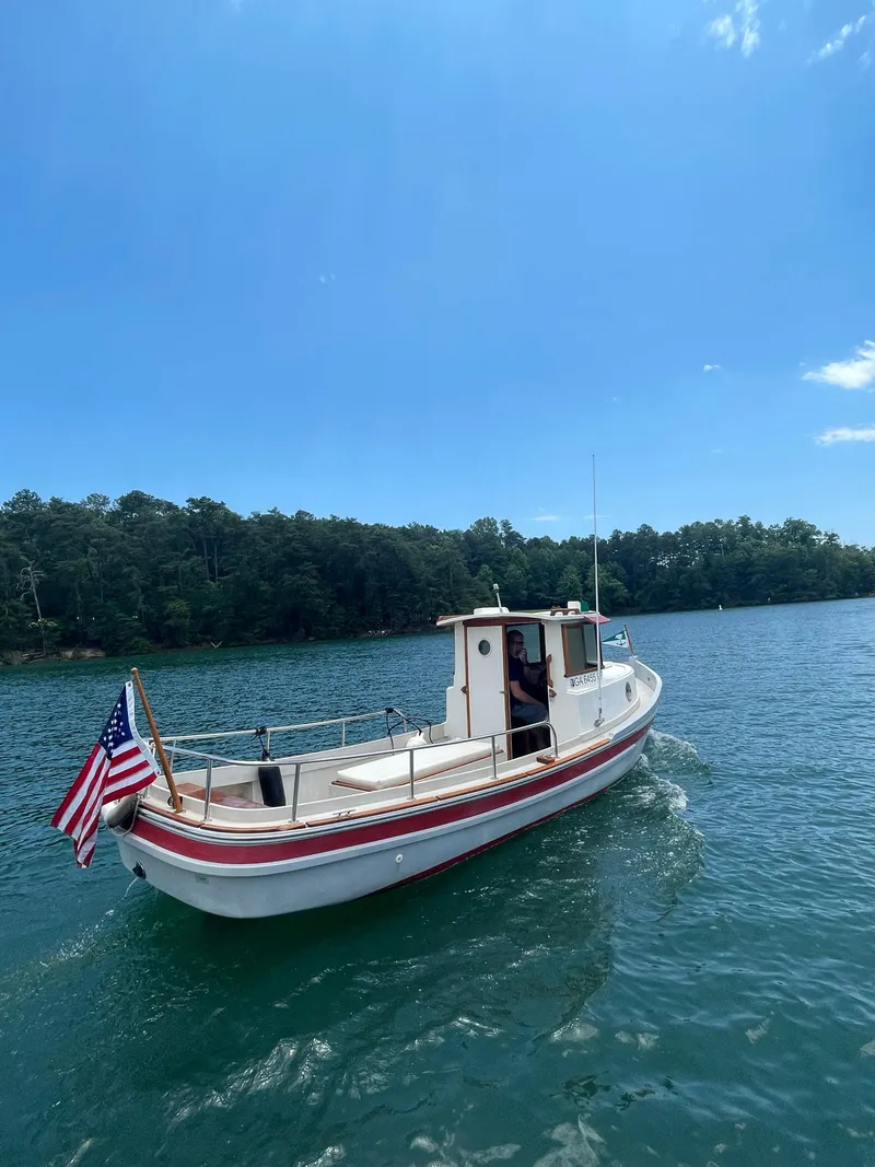 Slide: The Image of 1990 Ranger Tugs R21 Classic boat on a serene lake with American flag. - 11