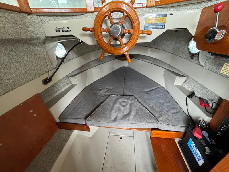 Slide: The Image of 1990 Ranger Tugs R21 Classic interior with wooden steering wheel and cushioned seating. - 18