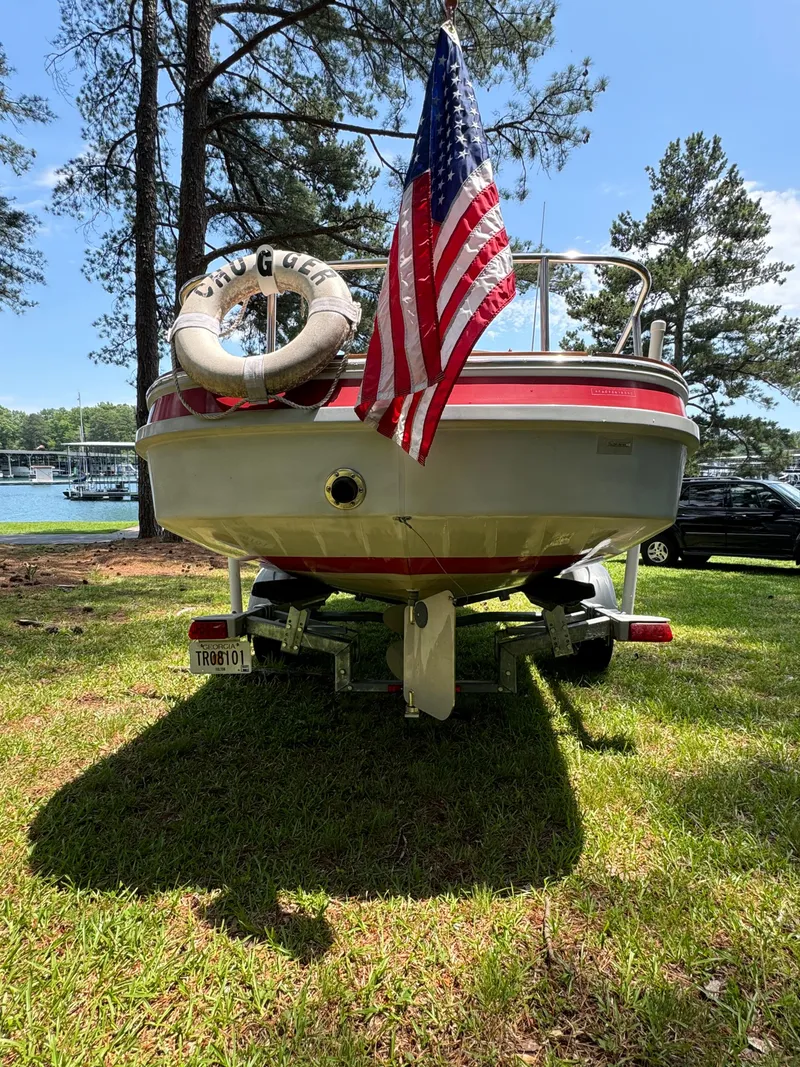 Slide: The Image of 1990 Ranger Tugs R21 Classic boat with American flag, parked on grass by a lake. - 5