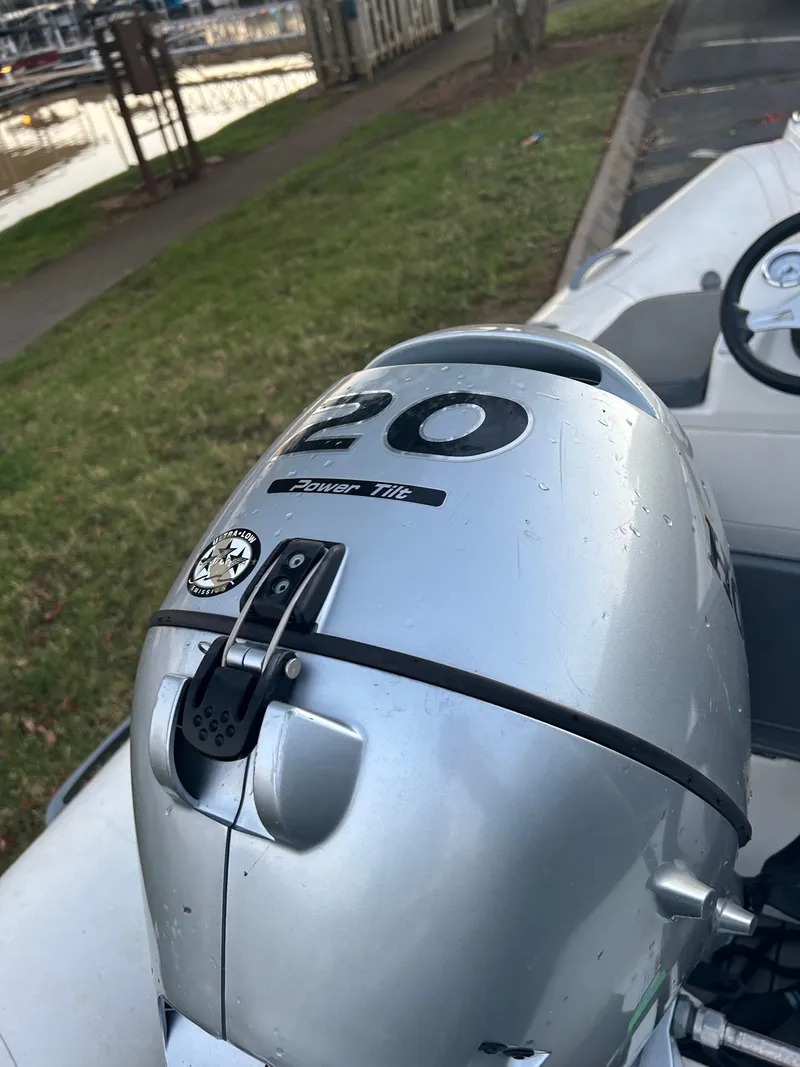 Slide: The Image of 2022 Brig Falcon Tender 300 with 20HP outboard motor, parked near a marina. - 20