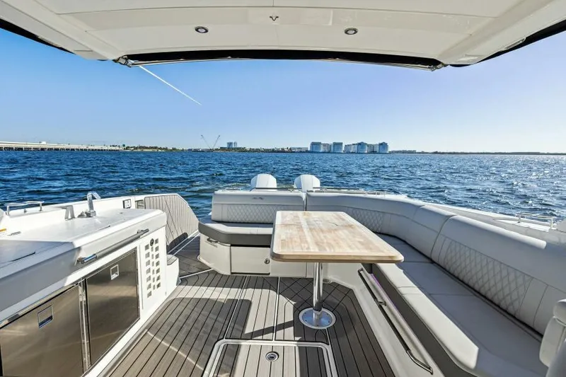 Slide: The Image of 2023 Sea Ray SLX 400 OB boat interior with seating and table, overlooking ocean view. - 8